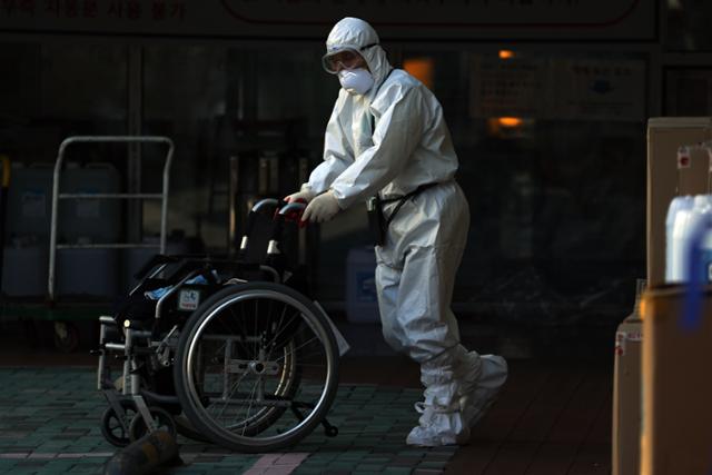 30일 서울 구로구 한 요양병원에서 레벨D 방호복을 입은 병원 관계자가 휠체어를 끌고 있다. 연합뉴스