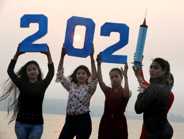 30일(현지 시간) 인도 보팔에서 2021년을 나타내는 숫자 팻말을 든 여성들이 새해를 맞아 기념 촬영을 하고 있다. 숫자 2021의 마지막 ‘1’은 주사기로 표현해 코로나19 퇴치를 기원하는 마음을 담았다./EPA연합뉴스