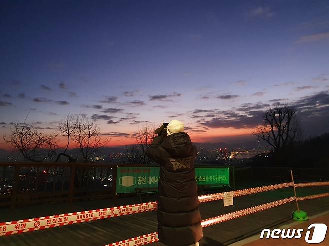 새해 첫날인 1일 오전 6시께 서울 용산구 남산에서 한 시민이 출입통제된 전망대 앞에서 일출을 기다리고 있다. © 뉴스1 김근욱 기자