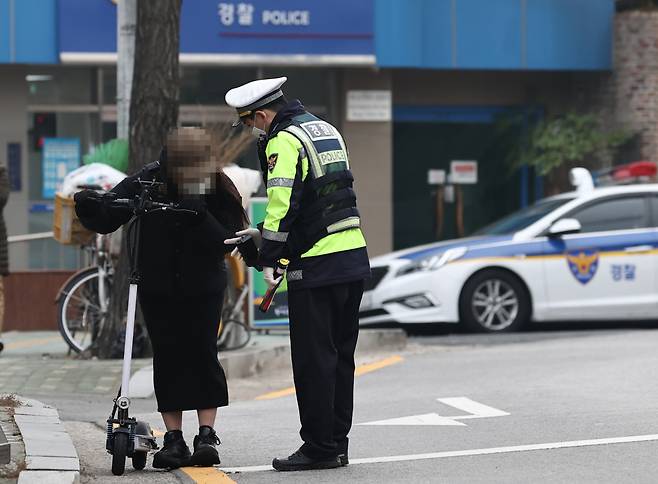 Police promote revised laws on e-scooters nearby a university campus on Dec. 10. (Yonhap)