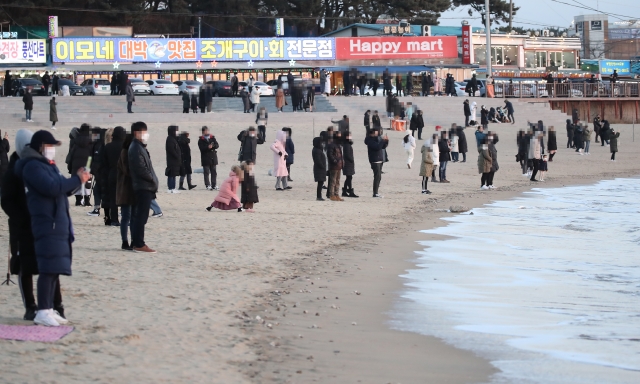 지난달 31일 인천 을왕리 앞 바다를 찾은 시민들이 올해 마지막 해넘이를 바라보고 있다. 연합뉴스