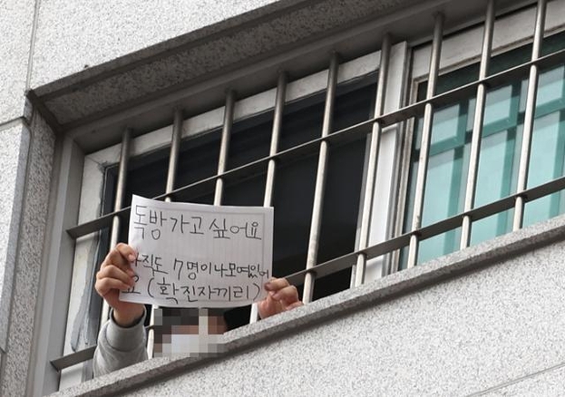 3일 오후 코로나19 확진자가 다수 발생 중인 서울 송파구 동부구치소에서 한 수용자가 취재진에게 '독방 가고 싶어요. 아직도 7명이나 모여 있어요(확진자끼리)'라고 적은 메모를 보여주고 있다. /연합뉴스