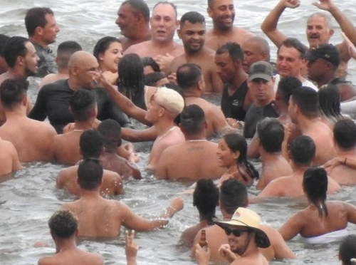 보우소나루 대통령(오른쪽 위 흰옷 입은 사람)이 지난 1일(현지시간) 해변에서 피서객들과 뒤엉켜 물놀이를 즐기고 있다./연합뉴스=브라질 뉴스포털 G1
