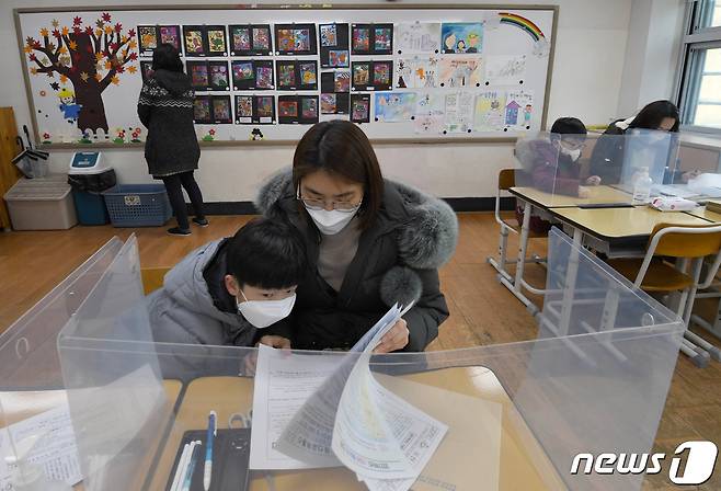 6일 서울 용산구 용산초등학교에서 어머니와 아이가 입학서류를 작성하고 있다. 2021.1.6/뉴스1 © News1 사진공동취재단