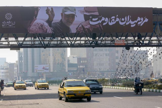 지난달 30일 이란 수도 테헤란의 고속도로에서 올해 초 미국의 무인기 공격으로 폭사한 혁명수비대 쿠드스군 사령관 가셈 솔레이마니를 그린 대형 간판 아래로 차들이 질주하고 있다. 이란은 내년 1월 3일 솔레이마니 사망 1주기를 맞는다. 테헤란=AFP 연합뉴스