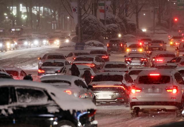 서울 전역에 대설주의보가 발효된 6일 오후 서울 삼성역 인근 도로에서 시민들이 차를 밀고 있다. 연합뉴스