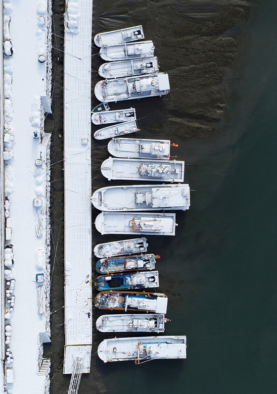 Fishing boats covered with snow are moored at Seoldo Port in Yeonggwang County, South Jeolla, on Wednesday morning. [YONHAP]