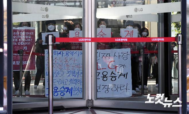 지난 4일 오전 서울 여의도 LG트윈타워 로비에서 청소노동자들이 고용승계를 촉구하는 피켓을 들고 있다. 황진환 기자