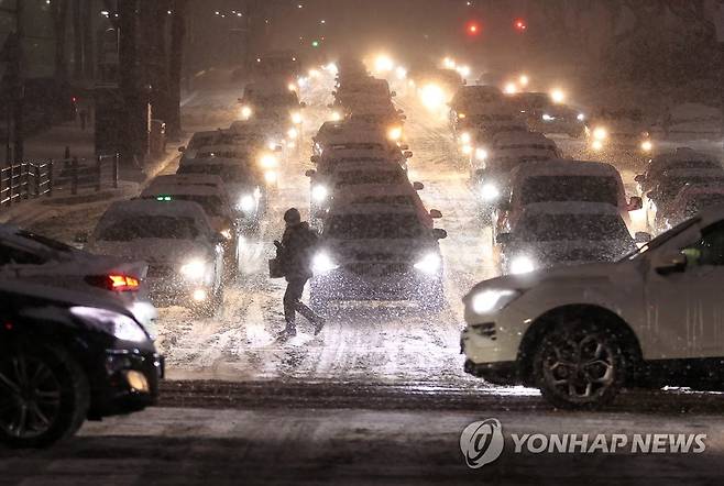 폭설에 힘겨운 퇴근길 (서울=연합뉴스) 이지은 기자 = 서울 전역에 대설주의보가 발효된 6일 오후 서울 삼성역 인근에서 한 시민이 횡단보도를 건너고 있다. 2021.1.6 jieunlee@yna.co.kr