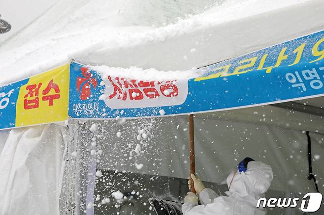 대설특보가 내려지는 등 한파가 기승을 부리는 7일 오전 광주시청 광장에 설치된 코로나19 임시 선별검사소에서 방역요원들이 천막 위에 쌓인 눈을 털어내고 있다. 2020.1.7 /뉴스1 © News1 황희규 기자