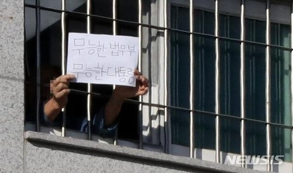 6일 서울 송파구 서울동부구치소에서 한 수용자가 종이에 쓴 글을 취재진에게 보여주고 있다. 내용은 '무능한 법무부 무능한 대통령'이라고 적혀있다. /뉴시스
