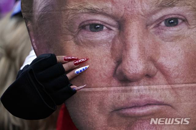 [워싱턴=AP/뉴시스] 민주당 조 바이든의 제46대 미국 대통령 당선을 인정하는 6일 선거인단 인증을 앞두고 이에 반대하는 트럼프 지지자들이 워싱턴에 모여 '미국을 구하자'라는 정치집회를 준비하고 있다. 사진은 집회에 참석하는 한 여성 지지자가 트럼프의 얼굴을 크게 확대한 사진 간판을 가슴 앞에 들고 있는 모습이다. 2021. 1. 6.