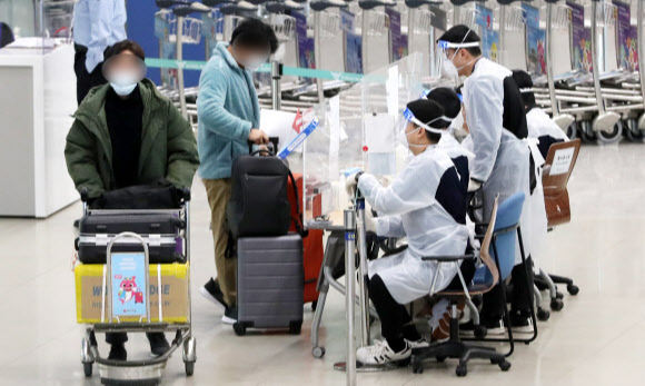 지난 6일 인천국제공항 입국장에서 방역 관계자들이 해외 입국자에게 동선을 안내하고 있다. 뉴스1
