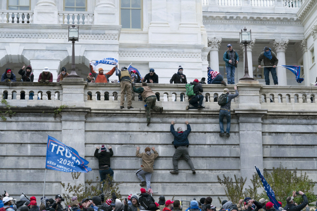 도널드 트럼프 미국 대통령 지지 시위대가 6일(현지시간) 워싱턴DC 연방의회 의사당 서쪽 벽을 기어오르고 있다. /AP=연합뉴스