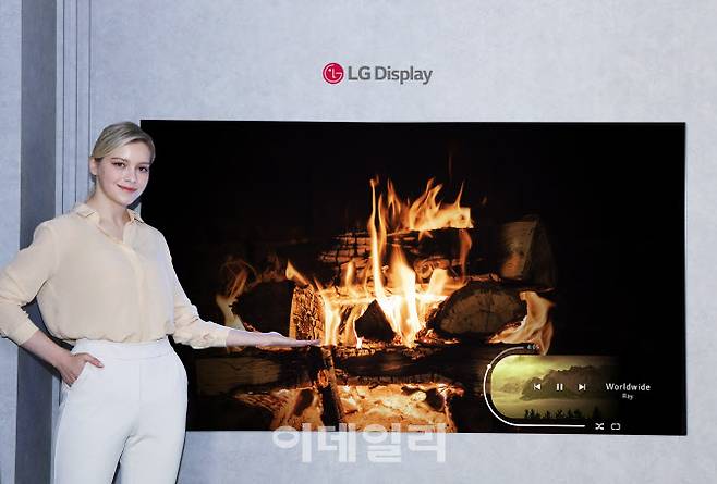 LG디스플레이 모델이 신규 OLED 소자가 적용된 77인치 차세대 OLED TV 패널을 소개하고 있다. (사진=LG디스플레이)