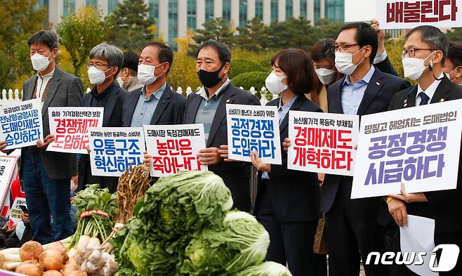 21일 서울 여의도 국회 앞에서 열린 '가락시장 공정경쟁 도입 촉구 기자회견'에서 전국농민회총연맹, 한국소비자연맹, 한국마트협회 관계자들과 박주민 더불어민주당 의원이 피켓을 들고 있다. 2020.10.21/뉴스1 © News1 안은나 기자