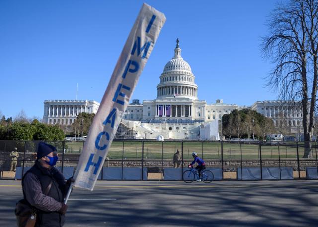 미국 시민이 10일 워싱턴 국회의사당 앞에서 '탄핵'(IMPEACH)이란 단어가 적힌 깃발을 들고 시위를 벌이고 있다. 미 민주당은 11일 도널드 트럼프 대통령 탄핵소추안을 발의했다. 워싱턴=AFP 연합뉴스