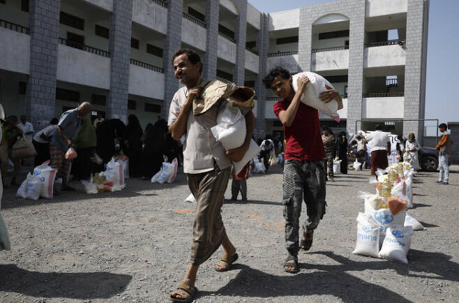 내전이 일어난 예멘에서 시민들이 구호단체가 나눠준 식량을 들고 걸어가고 있다. /EPA연합뉴스