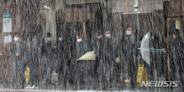 [서울=뉴시스]이영환 기자 = 눈이 내리고 있는 12일 오후 서울 중구 하나은행 앞에서 시민들이 대기하고 있다. 2021.01.12. 20hwan@newsis.com