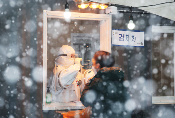 A man gets tested for the coronavirus Tuesday at Seoul Station Square amid heavy snow. [YONHAP]