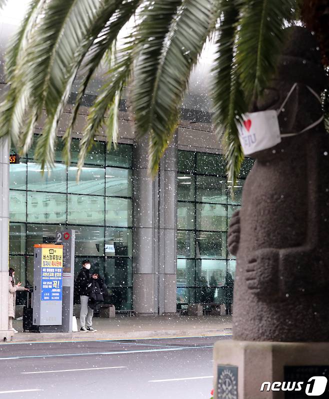 제주에 첫 눈이 내린 14일 오후 제주국제공항에서 관광객들이 주차장으로 이동하고 있다. 2020.12.14/뉴스1 © News1 오현지 기자