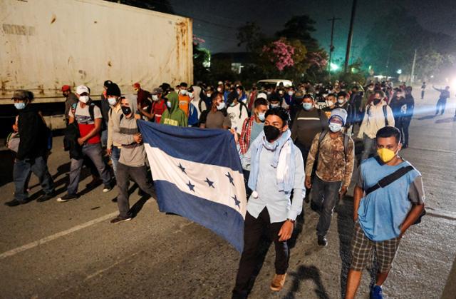 온두라스 산페드로술라에서 14일 중남미 이민자 행렬(캐러밴)이 국기를 들고 고속도로를 따라 미국을 향해 걸어가고 있다. 산페드로술라=로이터 연합뉴스