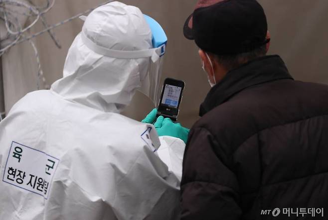 [서울=뉴시스]고승민 기자 = 서울지역 코로나19 신규 확진자가 0시 기준 127명 발생, 53일만에 최소 증가세를 기록한 15일 서울 청량리역 임시선별검사소에서 육군 현장지원팀 대원이 어르신에게 휴대폰 안내를 하고 있다. 2021.01.15. kkssmm99@newsis.com