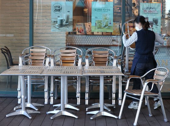 17일 서울 시내 한 카페에서 종업원이 외부 좌석을 정리하고 있다. 연합뉴스