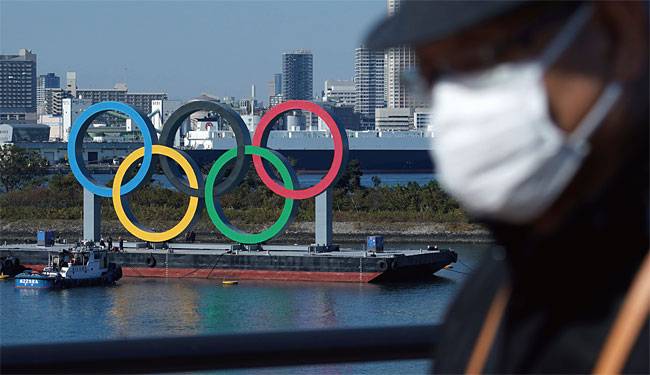 마스크를 쓴 일본인 남성 뒤로 올림픽 상징인 오륜이 보인다. 사진 AP연합