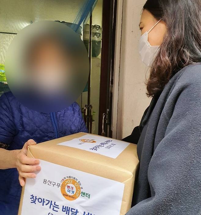 15일 용산구청 공무원이 푸드마켓 재가서비스 이용자에게 식료품을 전달하고 있다. / 자료제공=용산구청