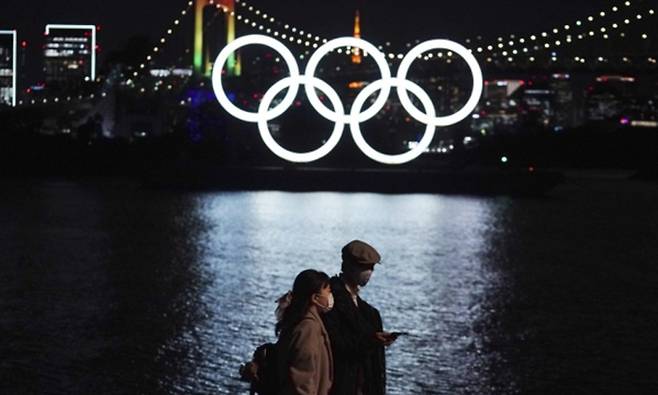 사진은 작년 12월1일 도쿄 오다이바 해양 공원에 설치된 오륜 조형물 앞을 행인들이 걷고 있는 모습. 도쿄 AP=연합뉴스