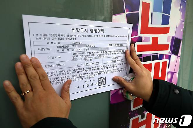 대구 노래연습장 도우미들의 신종 코로나바이러스 감염증(코로나19) 집단감염 발생으로 방역에 비상이 걸린 가운데 21일 오후 수성구청 관계자들이 관내 노래연습장에 집합금지 행정명령 안내문을 붙이고 있다. 대구시는 노래연습장 1602곳에 대해 21일 0시부터 31일 자정까지 집합금지 행정명령을 내렸다. 2021.1.21/뉴스1 © News1 공정식 기자