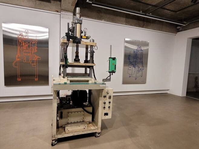 서울 독산동 공단지구 노동자 숙소를 리모델링한 ‘예술의 시간’에서 선보이고 있는 ‘속도와 무게의 [ ] 균형’ 전시장 일부. 사진은 김상현 작가의 설치작품이다. 공단에서 쓰다가 퇴역한 액압 프레스 기계 실물을 오브제로 전시장에 들여왔다. 기계 뒤쪽 벽에는 프레스 기계의 모습을 공단의 생산물인 스테인리스 판에 여러 색깔로 그린 정물 이미지를 함께 배치해 지금까지 흘러온 공단의 시간들을 반추하게 한다.