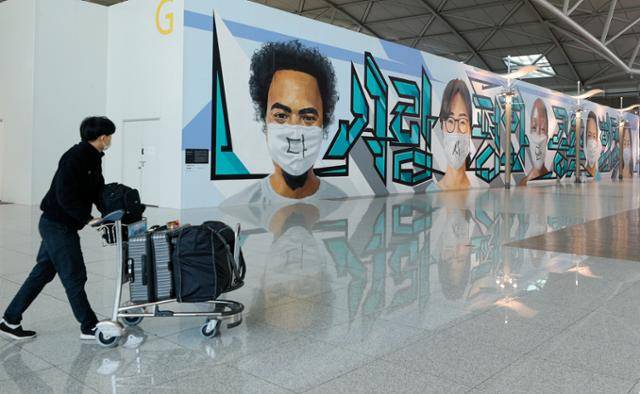 국내 신종 코로나바이러스 감염증(코로나19) 확진자가 처음 발생한 지 1년째 되는 날인 20일 인천국제공항 1터미널 출국장에서 공사장 가림막에 코로나 극복을 염원하는 그래피티가 그려져 있다. 뉴스1