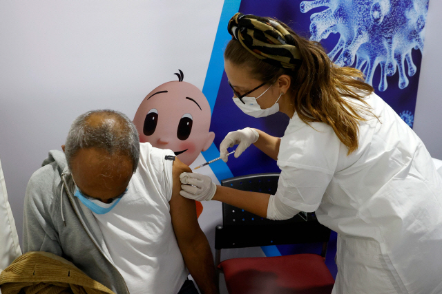 이스라엘의 네타냐 경기장에 마련된 임시 접종시설에서 의료진이 지난 20일 한 남성에게 코로나19 백신을 주사하고 있다. /AFP=연합