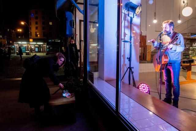 체코의 수도 프라하에서 21일 한 여성이 문닫은 상점 안에서 기타연주를 하는 공연가를 위해 감상요금을 내고 있다. 프라하=AFP 연합뉴스