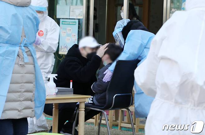 24일 오전 광주 북구 신용동 한 어린이집에서 한 학부모가 코로나19 검사를 받는 자녀를 안심시키고 있다. 전날 이 어린이집 원장이 코로나19에 확진돼 이날 오전 원생 등 200여명에 대한 전수검사가 진행됐다.2021.1.24/뉴스1 © News1 허단비 기자