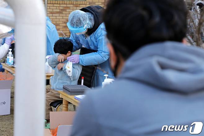 24일 오전 광주 북구 신용동 한 어린이집에서 한 학부모가 코로나19 검사를 받는 아들을 다독이고 있다.2021.1.24/뉴스1 © News1 허단비 기자