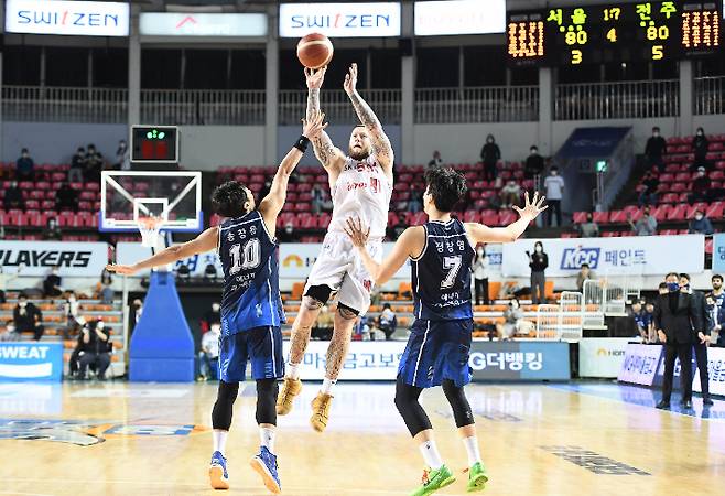 SK 닉 미네라스(가운데)가 24일 KCC와 원정에서 상대 겹수비를 넘어 종료 직전 위닝샷을 시도하고 있다. 전주=KBL