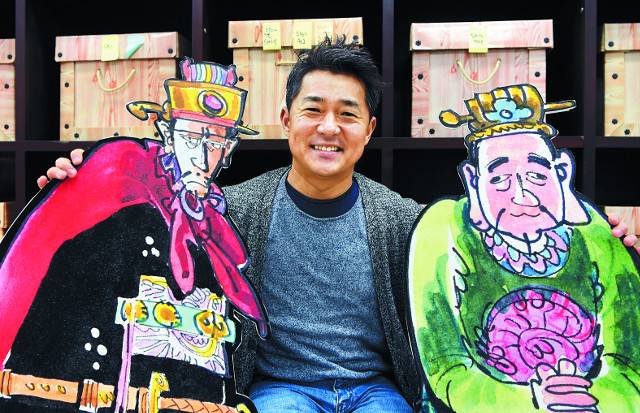 고(故) 고우영 화백의 차남 고성언 실장이 지난 21일 경기도 김포시 사무실에서 ‘고우영 삼국지’ 캐릭터 조조(왼쪽), 유비와 포즈를 취했다. 고 화백은 삼국지에서 유비를 자신의 모습으로 그리고 ‘쪼다’로 표현하기도 했다. 고 실장 뒤로 고 화백이 생전에 남긴 원고가 작품별로 보관돼있다. 김포=권현구 기자