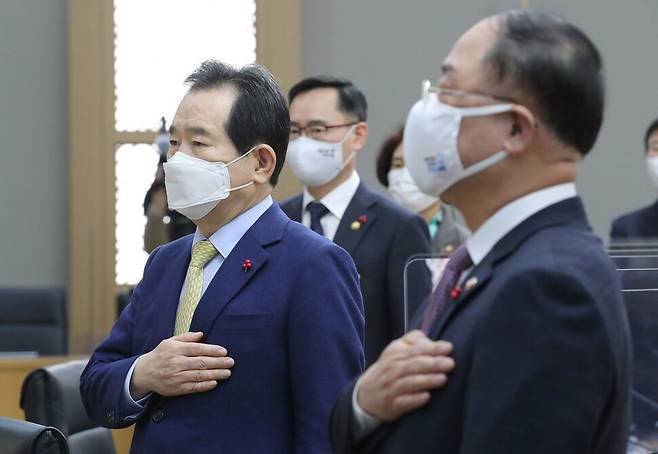 정세균 국무총리(왼쪽)가 26일 오전 세종시 정부세종청사에서 열린 국무회의에서 참석한 국무위원들과 국기에 경례하고 있다. 오른쪽은 홍남기 경제부총리 겸 기획재정부 장관. 연합뉴스
