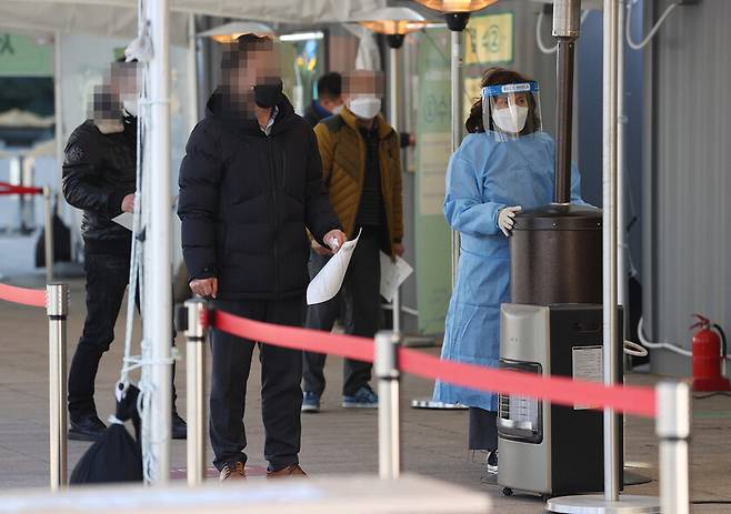 27일 오전 서울광장에 설치된 임시선별진료소에서 의료진이 난로에 손을 대고 있다. 연합뉴스