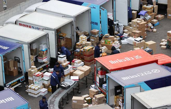 서울시내의 한 택배물류센터에서 28일 종사자들이 택배차량 앞으로 물품을 분류하고 있다. 연합뉴스