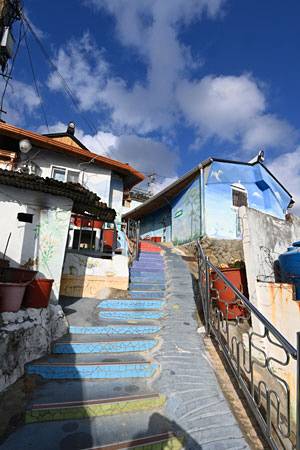 마산항이 한눈에 바라다보이는 비탈진 산동네에 조성한 벽화마을 산책길 ‘가고파꼬부랑길’. 누추한 산동네 골목의 담과 벽에 동화책 속 그림을 그려 넣었다.