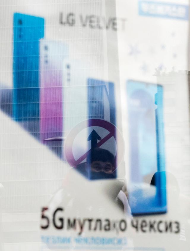 LG 스마트폰 광고가 붙은 서울 용산의 한 핸드폰매장 유리창에 교통표지판이 비치고 있다. 사진=연합뉴스