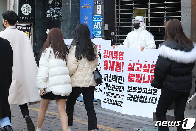 3일 오후 대구 중구 동성로의 한 클럽 앞에서 방역복을 입은 클럽 관계자가 1인 시위를 하고 있다. 코로나19로 인해 반복되는 집합금지 명령과 강제휴업에 심각한 경제적 위기를 겪고 있는 상인들의 피해보상을 촉구하기 위한 이날 1인 시위는 동성로 클럽골목 6개 클럽에서 진행됐다. 2021.2.3/뉴스1 © News1 공정식 기자