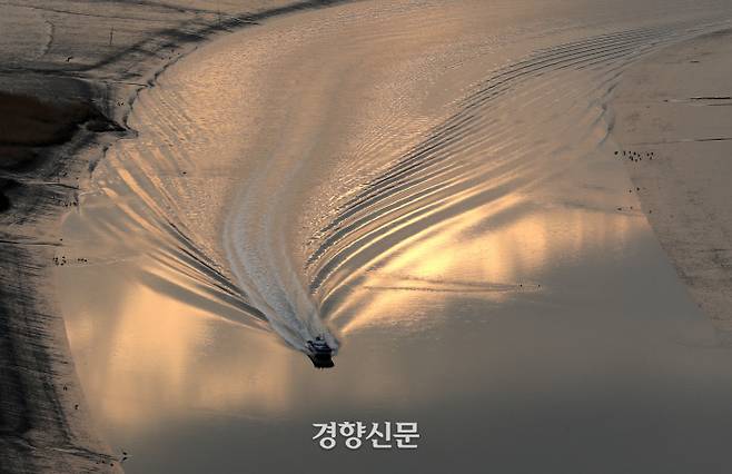 작은 배가 금빛 물살을 가른다. /강윤중 기자