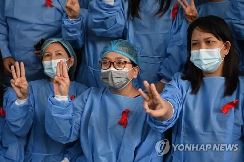 양곤 병원의 의료진이 쿠데타 항의 '시민 불복종' 의미로 아웅산 수치가 이끄는 민주주의 민족동맹(NLD) 상징색인 빨간 리본과 태국 반정부 시위에서 등장한 저항의 상징 '세 손가락 경례'를 하고 있다. 2021.2.3  [AFP=연합뉴스]