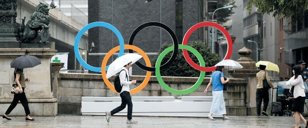 비 내리는 도쿄 시내에서 오륜 구조물 옆을 지나가는 일본 시민들. /AP 연합뉴스