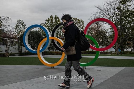 TOKYO, JAPAN - JANUARY 12: A woman wearing a face mask runs past the Olympic Rings on January 12, 2021 in Tokyo, Japan. Recent surveys by Kyodo News and Tokyo Broadcasting System found that over 80 percent of people in Japan who were questioned believe the Tokyo Olympics should be cancelled or postponed or that the Olympics will not take place. Tokyo remains in a second state of emergency amid a third wave of Covid-19 coronavirus that has seen infection rates climb to unprecedented levels. (Photo by Carl Court/Getty Images)